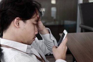 Depresyondaki işsiz Asyalı adam evde oturuyor. Başarısızlık ve işten çıkarma kavramı.