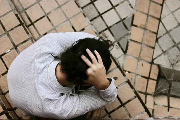 İşsiz ve stresli Asyalı genç iş adamının üst düzey görüşü yerde oturuyor. Başarısızlık ve işten çıkarma kavramı.