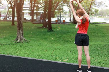 Sağlıklı genç Asyalı bir kadının sabah parkta koşmadan önce ellerini uzatması. Egzersiz ve egzersiz kavramı.