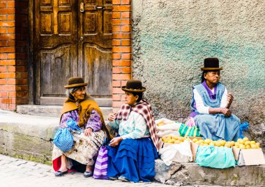 Coroico, Bolivia on 3rd May 2017: Group of indigenous woman selling local products on market clipart