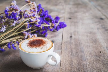 Bir fincan kahve ile menekşe buketi çiçek ahşap zemin zemin üzerine kurutulmuş.