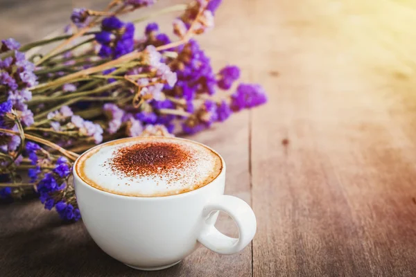 Bir fincan kahve ile menekşe buketi çiçek ahşap zemin arka plan, sabah güneşi üzerinde kurutulmuş.