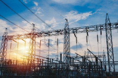 Sunset behind substation towers with blue sky clipart
