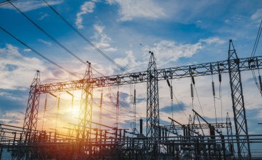 Sunset behind substation towers with blue sky clipart