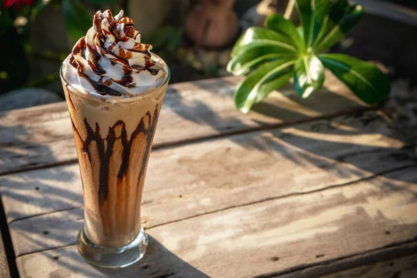 Coffee frappe with whipped cream on old wooden table in the morn