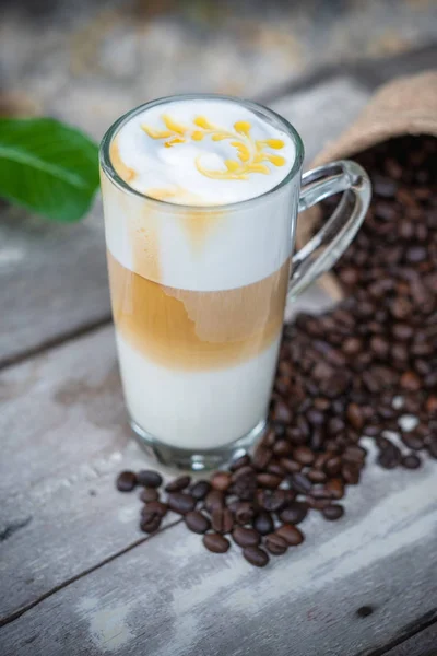 Горячий карамельный кофе в стакане с кофейными зернами — стоковое фото