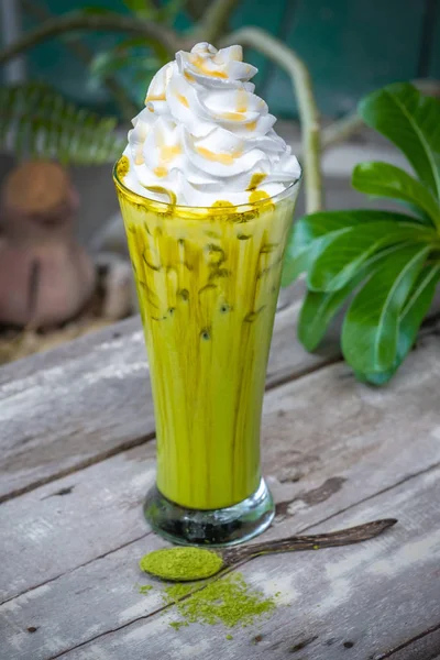 Es teh hijau Matcha dengan krim kocok di atas meja kayu — Stok Foto