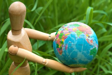Eearth globe in hands of wooden doll green energy and environmental protection concept clipart