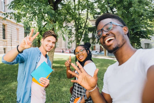 Eğitim, yaşam tarzı, eğlence ve teknoloji kavramı. Işınlanan gülümsüyor ile çok ırklı öğrenciler üniversite kampüs parkta açık çekim selfie için poz veriyor.