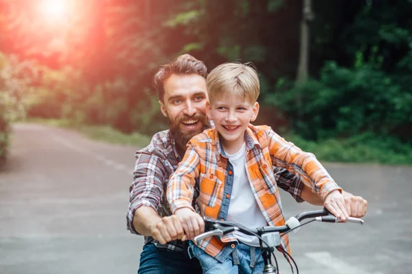Счастливый смеющийся отец с сыном на велосипеде. . — стоковое фото