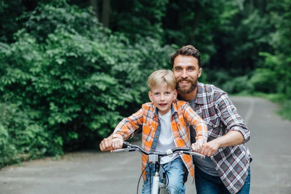 Счастливый улыбающийся отец с сыном на велосипеде . — стоковое фото