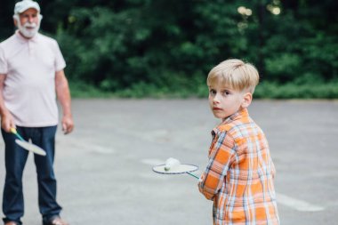 Sevimli küçük çocuk oyun alanında onun dedesi ile badminton oynuyor. Çocuklar için açık yaz etkinlikleri. Aile zamanı kavramı.