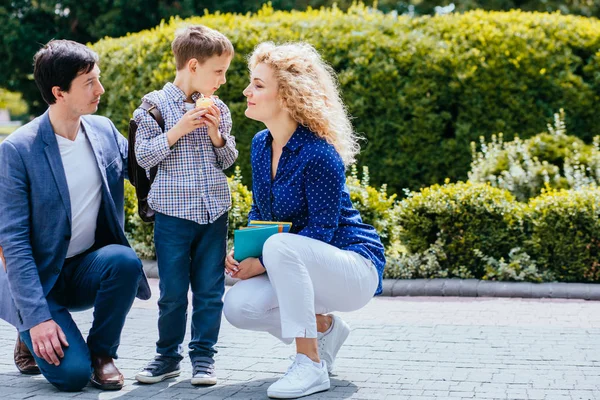 Mature parents saying goodbye to their little child near school.