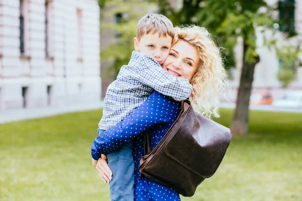 Счастливая блондинка кудрявая мать веселится со своим ребенком в летнем парке под открытым небом. Подросток обнимает маму на улице.  . — стоковое фото