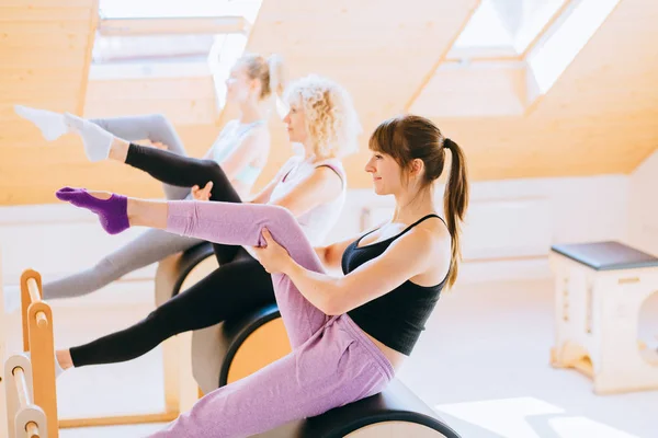 Группа сильных женщин сконцентрирована на упражнениях на бочках для пилатеса с инструктором женского пола в спортзале. Спортивное оборудование . — стоковое фото