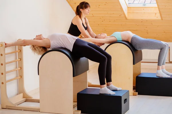 O grupo de mulheres aptas concentra-se em exercitar-se sincronicamente em barris de pilates com instrutora feminina no ginásio. Equipamento desportivo . — Fotografia de Stock