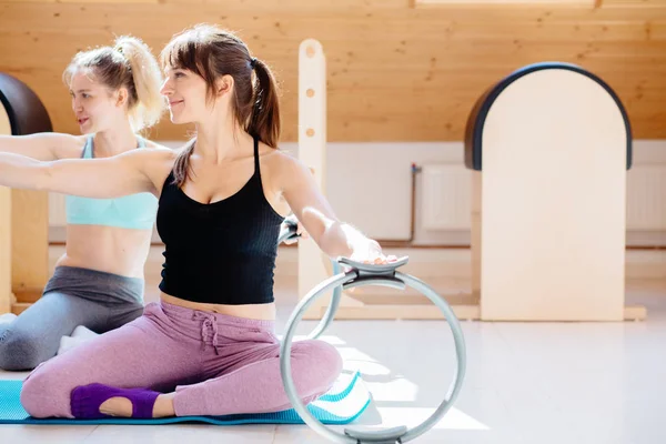 Young cheerful women making pilates exercises with fitness rings — Stock Photo, Image