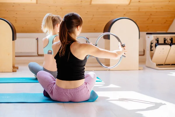 Jovem desportiva mulher atraente fazendo pilates tonificação exercício para braços e ombros com anel, fitness com pilates círculo mágico nas mãos, trabalhando fora, interior de perto. Força, conceito de bem-estar — Fotografia de Stock