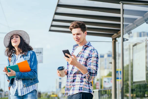 Viajeros turísticos consultando gps y guía desde un teléfono inteligente en una estación de tren — Foto de Stock