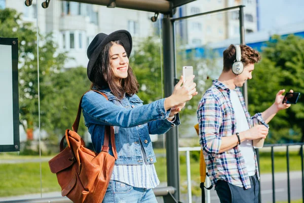Feliz europeo viajero pareja bloggers hombre y mujer extraños tomando selfie con teléfonos inteligentes en parada de tranvía durante las vacaciones de verano viaje aventura . — Foto de Stock