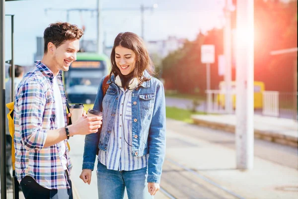 Joven feliz riendo pareja de pie en la parada de tranvía en el soleado día de verano . — Foto de Stock