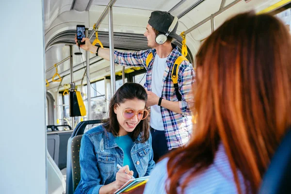 Jovem mulher linda com óculos de sol na cabeça está encostada na barra de ônibus e segurando sua mala de bagagem enquanto viaja de ônibus . — Fotografia de Stock