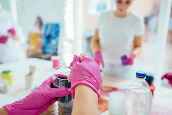 Close-up van de artiesten hand geperst uit een buis verf op een ezel. — Stockfoto