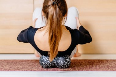 Kadın miyofasiyal rahatlama egzersizi için dublajı kullanıyor evde sırt üstü uzanmak için, fitness egzersizinden sonra, yüksek yoğunluktaki egzersizden sonra kas zorlanması, acının üstesinden gelmek, rehabilitasyon konsepti.