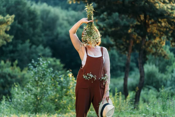 Dojrzała Kobieta Wieku Ukrywa Twarz Bukietem Dzikimi Rumiankami Brązowych Kombinezonach — Zdjęcie stockowe