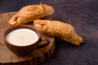 İki lezzetli croissants ve kahve fincanı kahverengi zemin üzerine