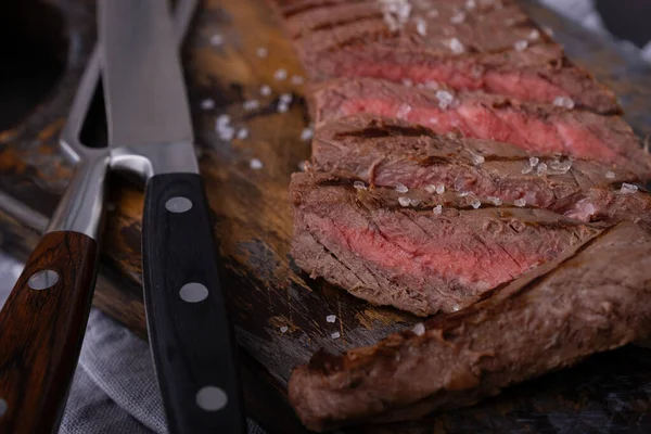 Rindersteak Großaufnahme Mit Messer Und Gabel Auf Schneidebrett Mit Salz lizenzfreie Stockfotos