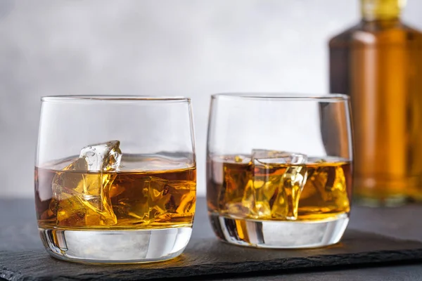 威士忌和带有波旁威士忌或白兰地的冰背景瓶 免版税图库照片