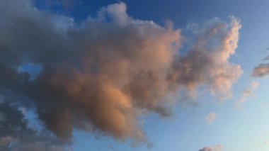 Sıcak bir ışıkla aydınlatılan bulutların gündoğumunda çekilmiş video kayıtları. Mavi gökyüzü bulutların hareketleri ve şekilleri için bir zemin sağlar.. 