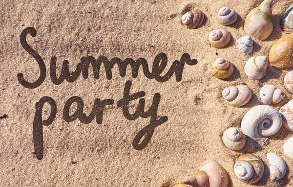 Summer party text drawn on a sand with a shells