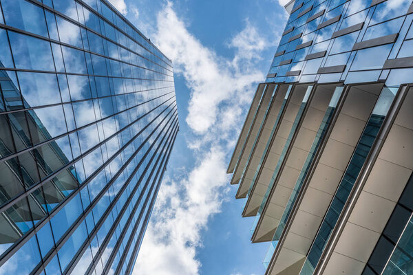 Clouds in a blue sky reflected in the windows of skyscrapers taken from below, a horizontal image of an urban landscape