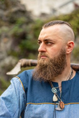 Boynunda baltası ve muskası olan uzun sakallı bir Viking savaşçısının portresi.