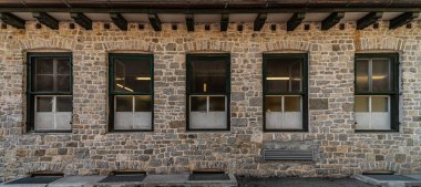 Temiz taşlardan oluşan bir bina ve dağ mimarisi üzerine dizilmiş bir dizi pencere.