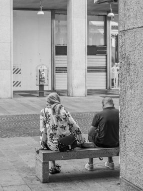 Milano 'nun göbeğindeki bir sokakta, bir bankta oturan iki kişi, siyah beyaz sokak fotoğrafçılığı.