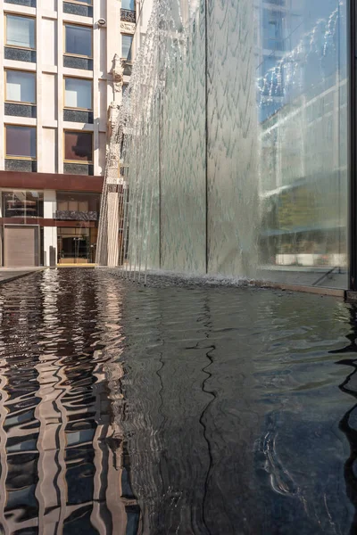 stock image Modern fountain with water splashes on a huge glass window, contemporary architecture in the city center