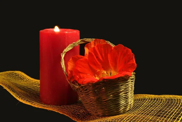 Kırmızı mum bir hasır sepet içinde çiçeklerle aydınlatılmış, bir spa. — Stok fotoğraf