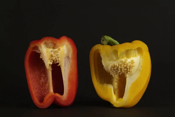 Trozos de pimientos amarillos y rojos sobre fondo negro — Foto de Stock