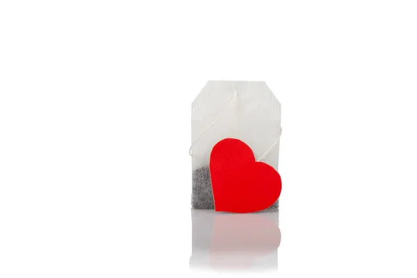 Close-up of tea bag with red heart tag on white background