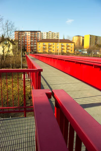 Steel red bridge over the railway in Frydek Mistek in the Czech Republic. In the background is the colored block of flats.