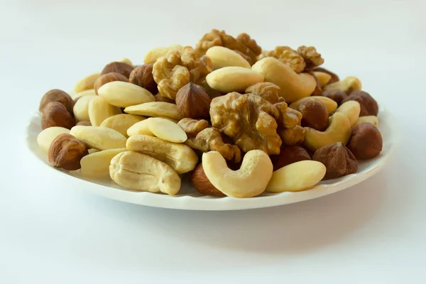 Nuts mixture - hazelnuts almonds walnuts cashew on a plate on a white background