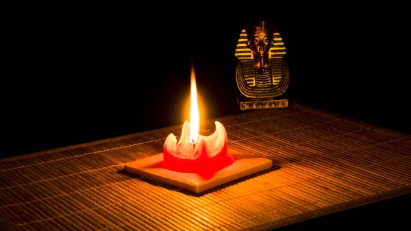 图坦卡蒙雕像在黑色背景的竹垫上被蜡烛点燃 — 图库照片