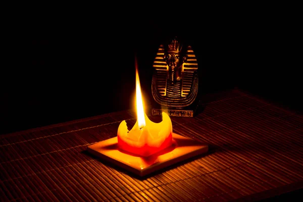 图坦卡蒙雕像在黑色背景的竹垫上被蜡烛点燃 — 图库照片