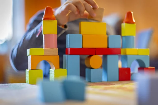 a child plays with colored wooden blocks at home.kid plays and builds buildings and towers with wooden colored blocks.