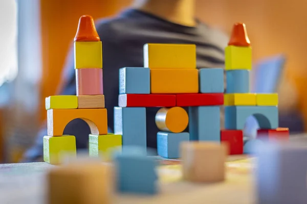 a child plays with colored wooden blocks at home.kid plays and builds buildings and towers with wooden colored blocks.