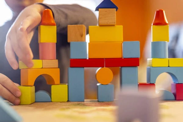 a child plays with colored wooden blocks at home.kid plays and builds buildings and towers with wooden colored blocks.