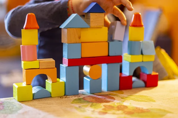 a child plays with colored wooden blocks at home.kid plays and builds buildings and towers with wooden colored blocks.